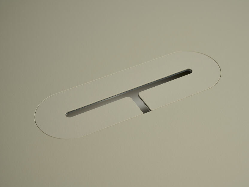 Eine eloxierte Aluminium-Ovalabdeckung für Kabel von Daniel Lorch, die auf einer Seite mit Vapoor-Linoleum bedeckt ist. Sie sitzt in der Aussparung der Tischplatte und organisiert effektiv Kabel, indem sie sie vor Abrieb schützt.