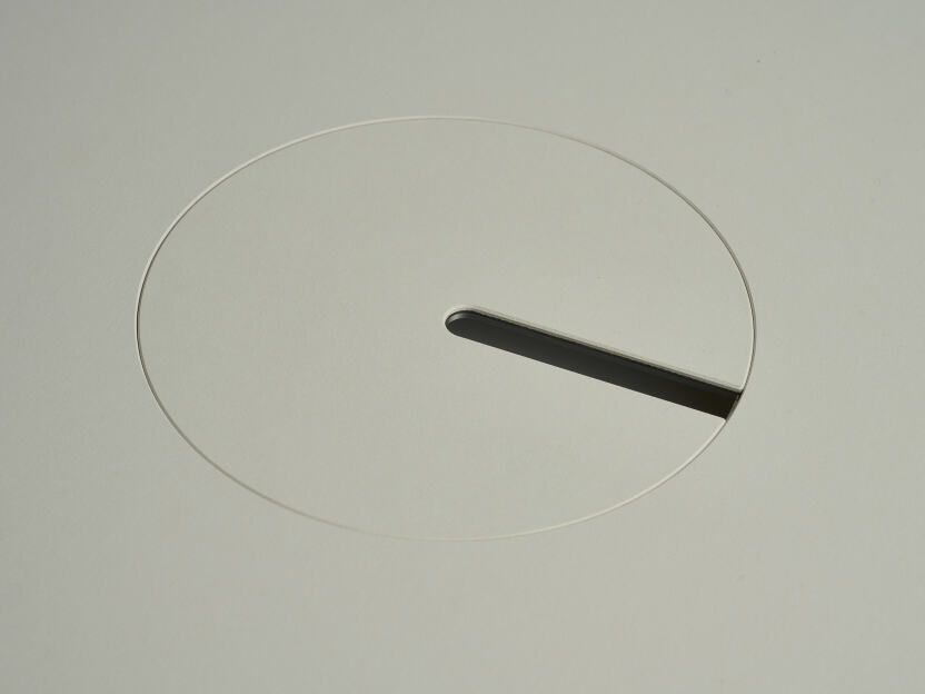 Eine eloxierte Aluminium-Rundabdeckung für Kabel von Daniel Lorch, die auf einer Seite mit Vapoor-Linoleum bedeckt ist. Sie sitzt in der Aussparung der Tischplatte und organisiert effektiv Kabel, indem sie sie vor Abrieb schützt.