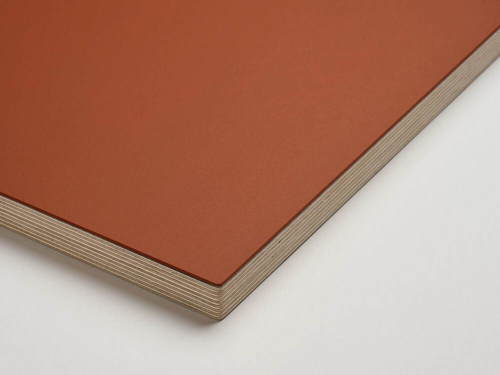 "Close-up view of a Faust tabletop with a rust-red linoleum surface and multiplex edge against a white background. "
