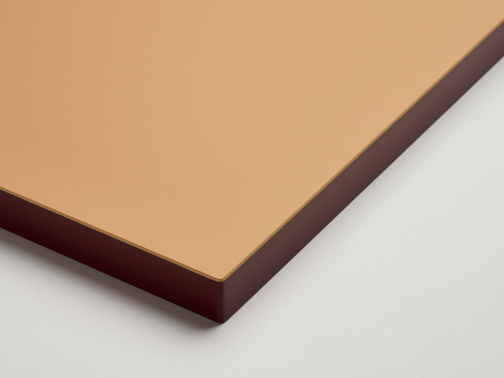 Detailed view of a Faust tabletop with a linoleum surface in a warm leather tone and burgundy linoleum edge against a white background.