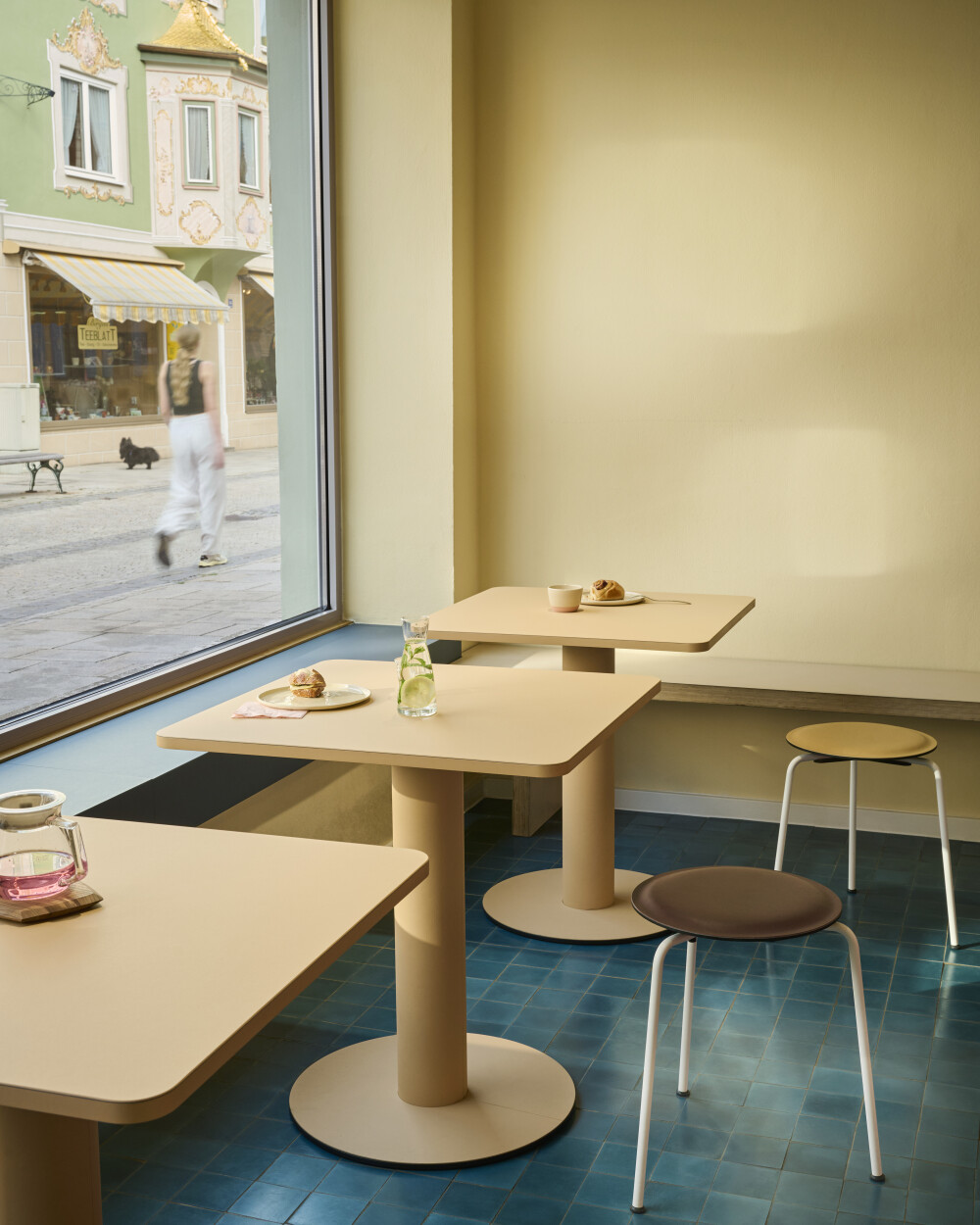 Kompakte SPOT Bistrotische mit quadratischen Tischplatten als Cafétische in einer Gastronomieumgebung.