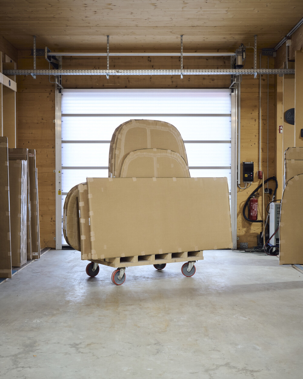 Verpackte Tischplatten von Faust auf rollender Palette vor geschlossenem Tor in der Produktionshalle – bereit für Versand.