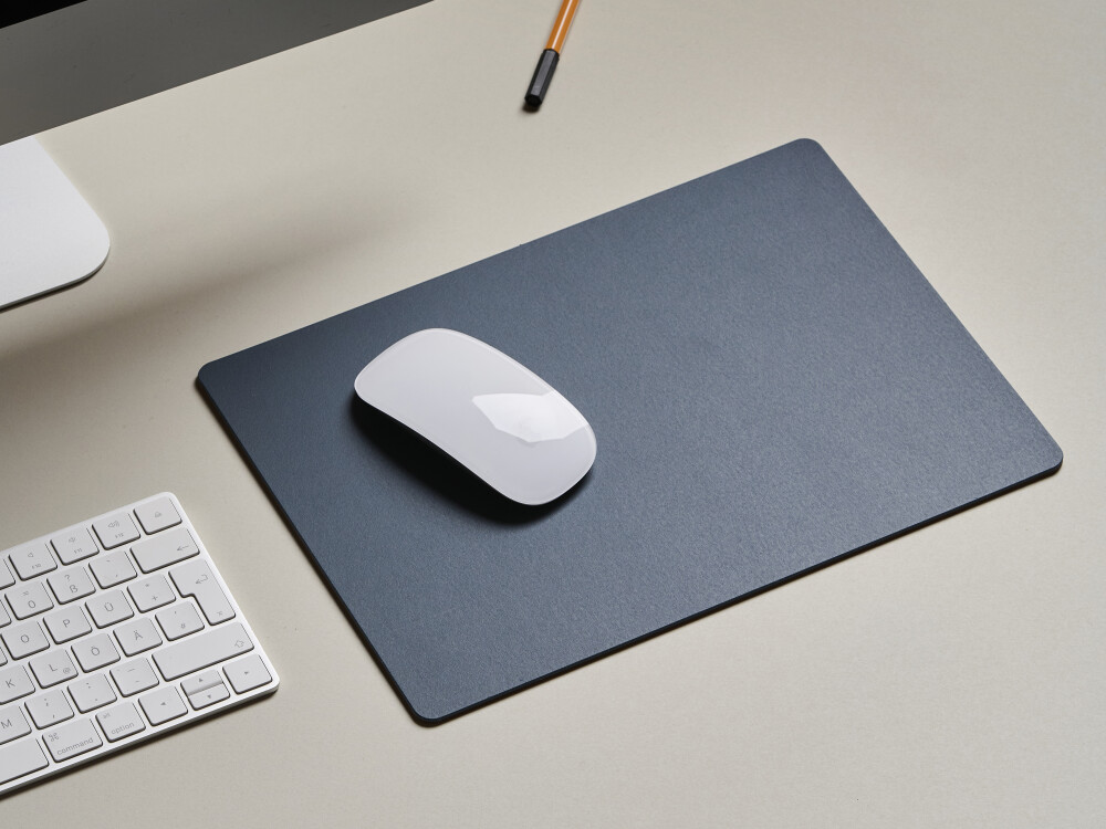 Tischplatte in hellgrau mit matter Linoleumoberfläche, kombiniert mit Mousepad in dunkelblau – minimalistisches Arbeitsplatz-Setting.