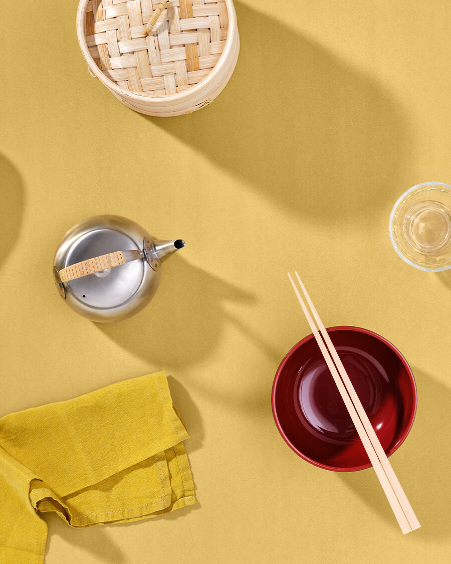 Untreated linoleum panel in natural yellow by Faust with teapot, bowl, chopsticks and napkin - a bird's eye view of a laid table.
