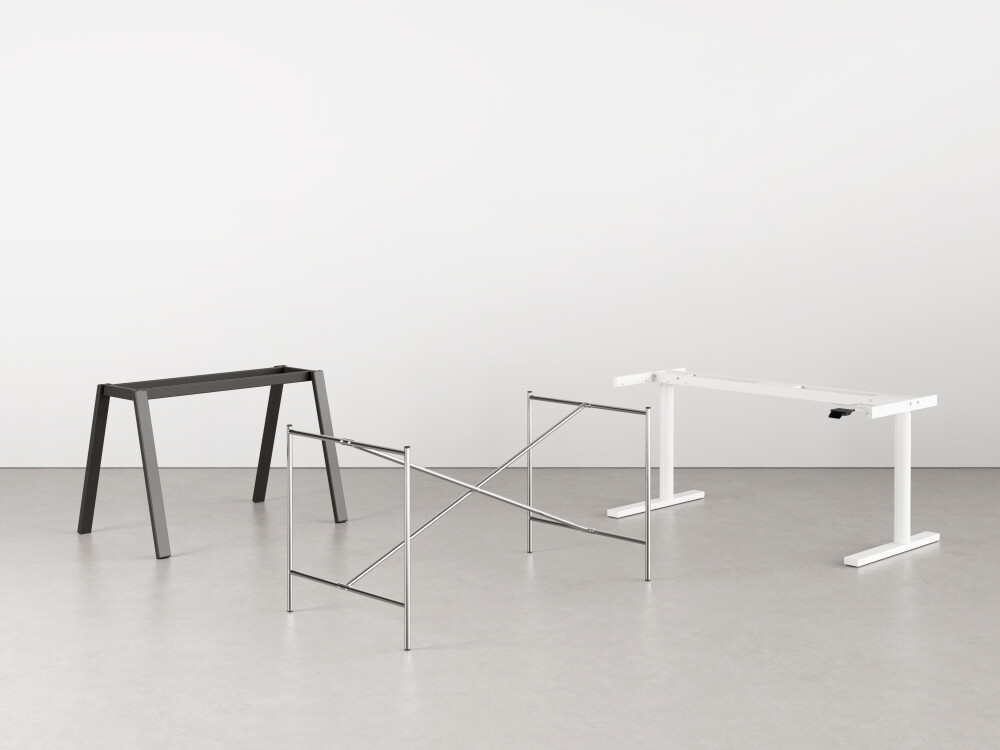 Three metal table frames from Faust in different versions - height-adjustable, powder-coated, arranged in the studio.