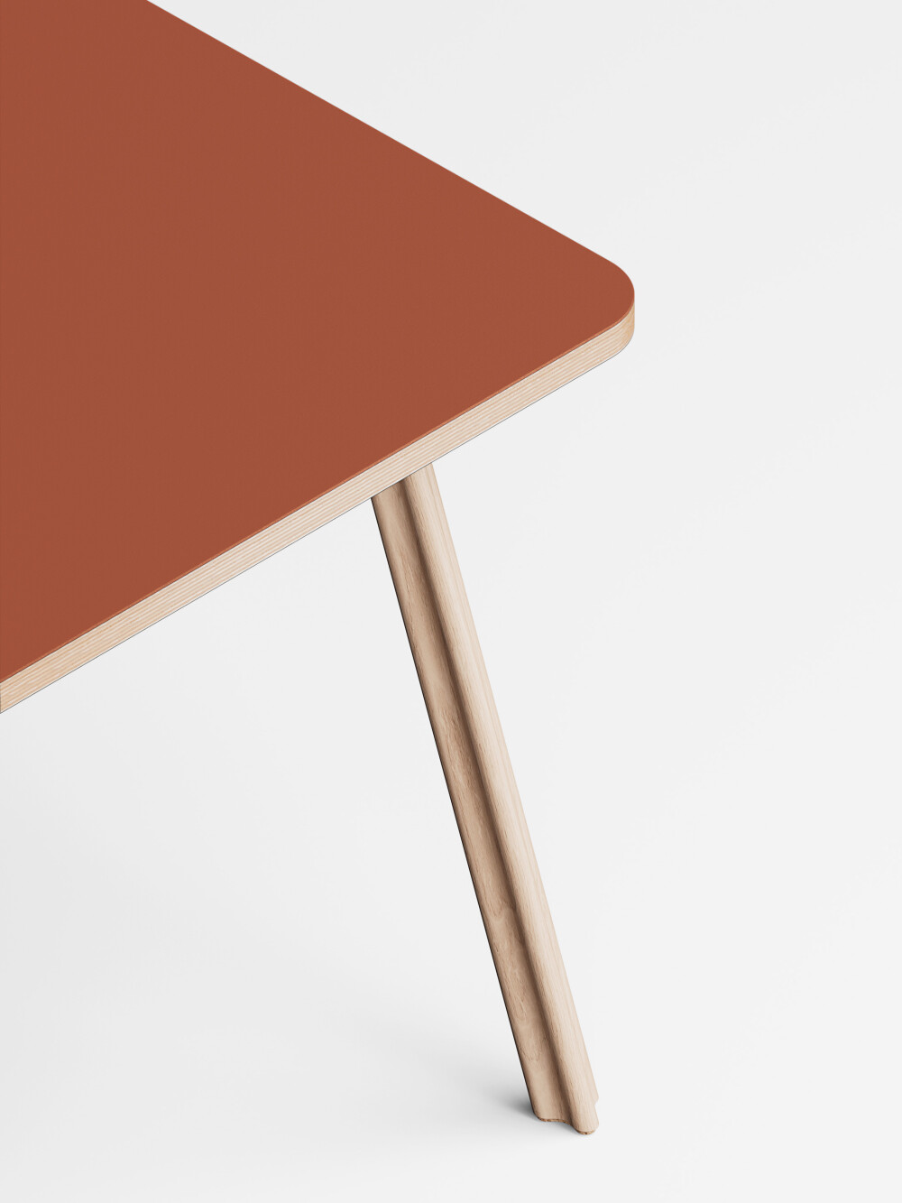 Close-up of the Beam table leg made of solid ash wood with cork feet on a blue linoleum tabletop.