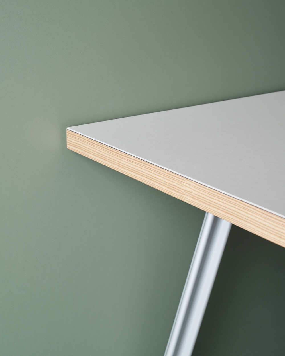Detailed view of a BEAM table with gray linoleum surface against a green background.