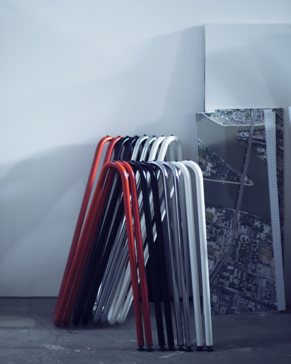 Several Sinus table trestles in different colours stacked against a wall for space-saving storage.