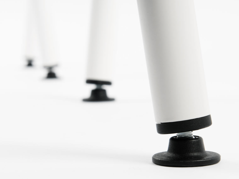 Close-up of the adjustable glides on the Sinus table trestle, which compensate for unevenness in the floor.