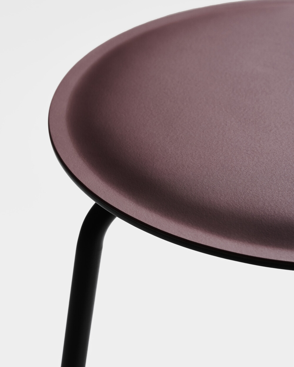Close-up of the RAVIOLI stool with burgundy linoleum seat and black steel legs.
